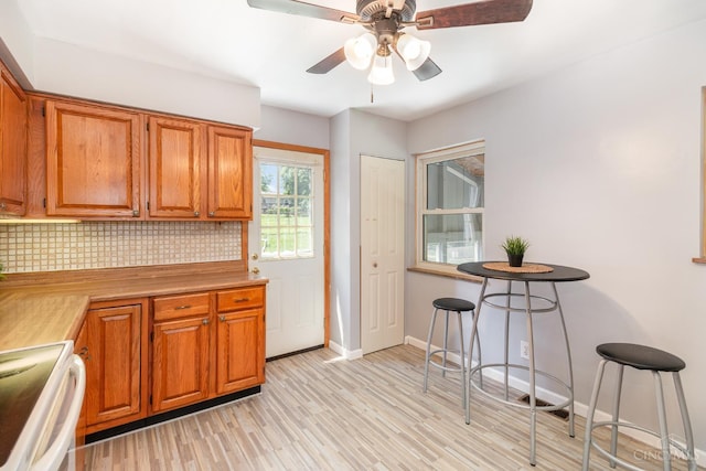 1127 Anderson Fry, Delhi Twp, OH 45238 - kitchen with white range with electric cooktop, tasteful backsplash, light wood-type flooring, a ceiling fan, and brown cabinetry