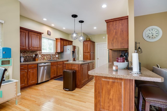 5088 Harvestdale Dr, Mason, OH 45040 - kitchen featuring stainless steel appliances, light wood-style floors, a peninsula, a breakfast bar, and decorative backsplash