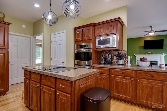 5088 Harvestdale Dr, Mason, OH 45040 - kitchen with black electric stovetop, stainless steel microwave, light wood-type flooring, a center island, and pendant lighting