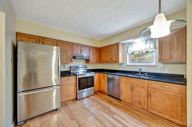 10854 Ponds Ln Unit 8, Sycamore Twp, OH 45242 - kitchen with appliances with stainless steel finishes, light wood-style flooring, under cabinet range hood, hanging light fixtures, and brown cabinets