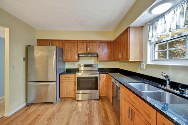 10854 Ponds Ln Unit 8, Sycamore Twp, OH 45242 - kitchen featuring stainless steel appliances, under cabinet range hood, light wood-type flooring, brown cabinets, and dark stone counters