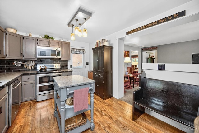 5744 Melody Ln, Milford, OH 45150 - kitchen featuring appliances with stainless steel finishes, light wood-style floors, decorative backsplash, hanging light fixtures, and gray cabinetry