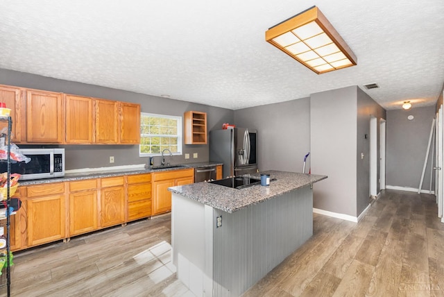 11818 Cloverlick Rd, Bethel, OH 45106 - kitchen featuring stainless steel appliances, light wood-style flooring, a textured ceiling, a kitchen island, and light stone counters