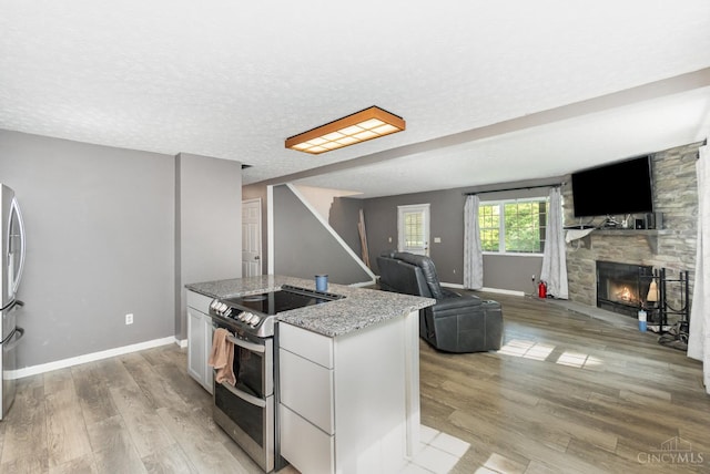 11818 Cloverlick Rd, Bethel, OH 45106 - kitchen featuring stainless steel appliances, a center island, light stone countertops, a stone fireplace, and open floor plan