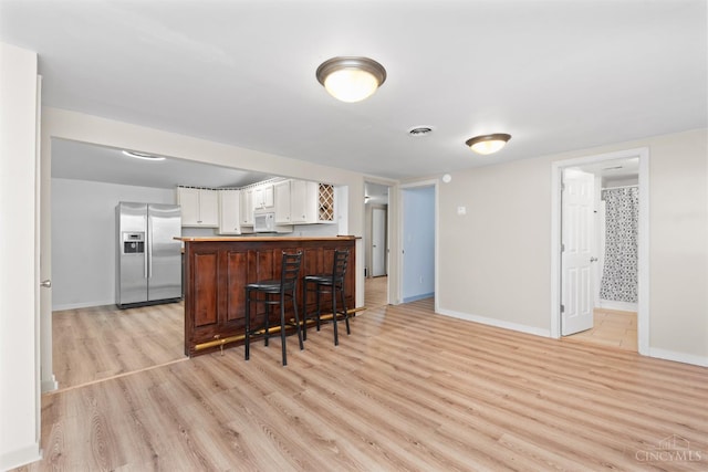 340 N E St, Bethel, OH 45106 - kitchen featuring stainless steel fridge, light wood-style flooring, white cabinetry, white microwave, and a peninsula