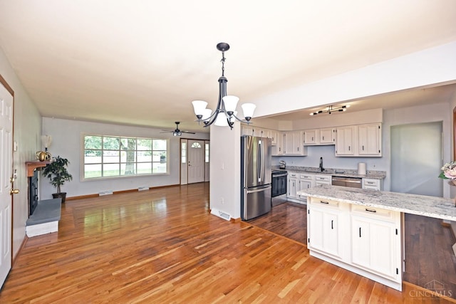 5428 Tallawanda Dr, Fairfield, OH 45014 - kitchen with stainless steel appliances, a chandelier, light wood finished floors, light stone counters, and open floor plan