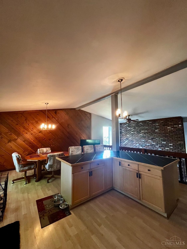 5674 Windsong Ln, Milford, OH 45150 - kitchen with light wood-type flooring, tile countertops, a chandelier, hanging light fixtures, and wooden walls