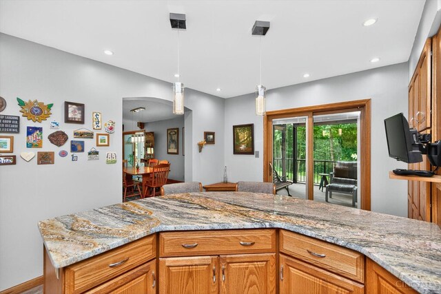 10869 Sand Run Rd, Whitewater Twp, OH 45030 - kitchen featuring light stone countertops, recessed lighting, decorative light fixtures, brown cabinetry, and arched walkways