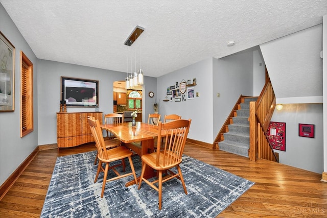 10869 Sand Run Rd, Whitewater Twp, OH 45030 - dining space featuring a textured ceiling, wood finished floors, and stairs