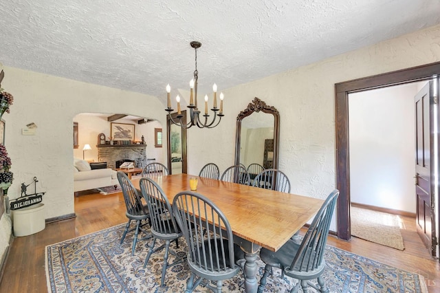 799 Millville Oxford Rd, Hamilton, OH 45013 - dining area featuring arched walkways, a textured wall, a fireplace, a textured ceiling, and wood finished floors