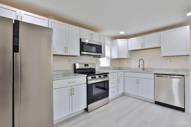 841 Willow Ave, Hamilton, OH 45013 - kitchen featuring appliances with stainless steel finishes, light countertops, white cabinets, light wood-style flooring, and recessed lighting