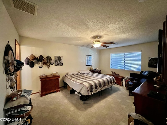 bedroom featuring light carpet, a textured ceiling, visible vents, and a ceiling fan