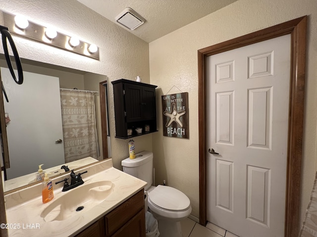 bathroom with visible vents, a textured wall, toilet, vanity, and tile patterned flooring