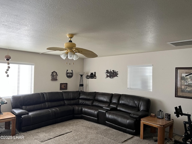 living area with light carpet, a textured ceiling, visible vents, and a ceiling fan