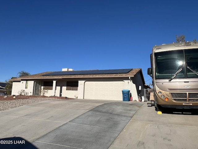 view of front of house with roof mounted solar panels, concrete driveway, an attached garage, and stucco siding