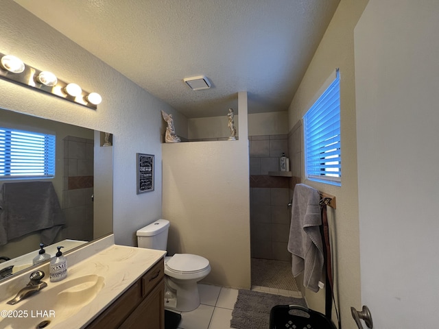 bathroom with toilet, tile patterned flooring, walk in shower, a textured ceiling, and vanity