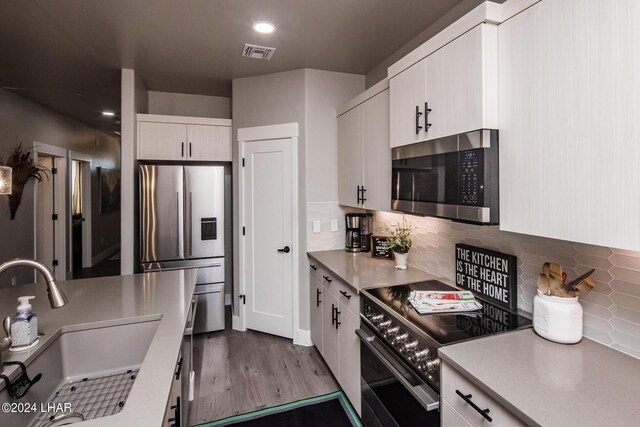 kitchen with white cabinetry, stainless steel appliances, sink, and tasteful backsplash