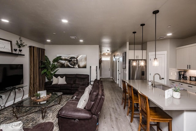 living room featuring sink and light hardwood / wood-style flooring