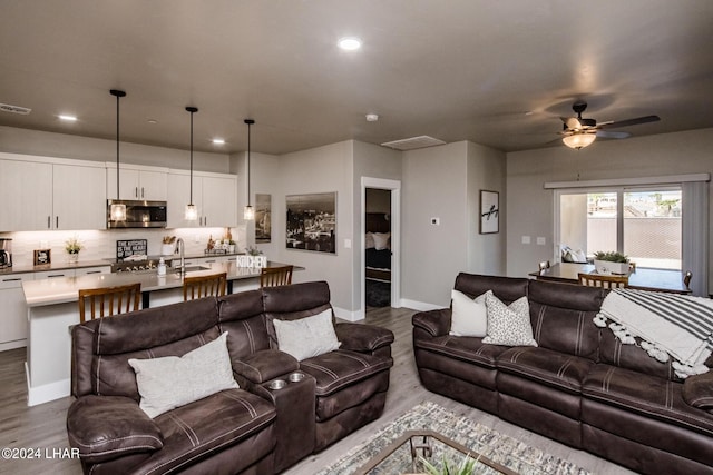 living room with wood-type flooring, sink, and ceiling fan