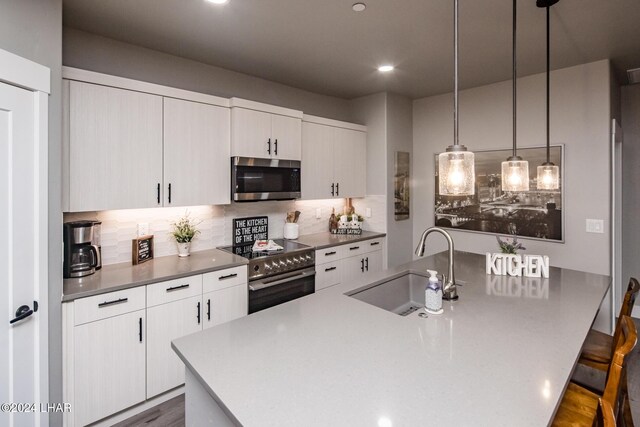 kitchen with a breakfast bar, decorative light fixtures, tasteful backsplash, sink, and stainless steel appliances