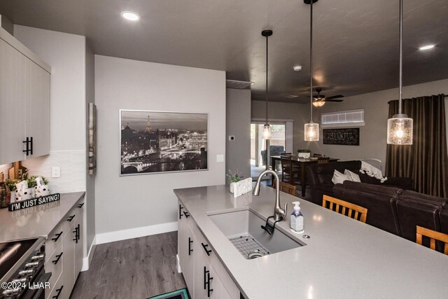 kitchen with sink, stainless steel range with electric cooktop, hanging light fixtures, dark hardwood / wood-style floors, and white cabinets