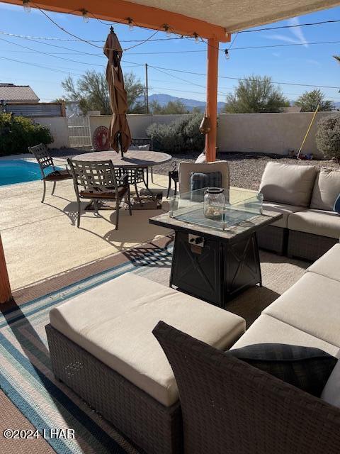 view of patio with a fenced in pool and an outdoor living space with a fire pit