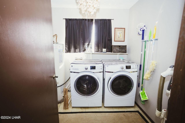 laundry room with an inviting chandelier, washing machine and clothes dryer, water heater, and light tile patterned floors