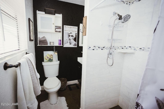 bathroom featuring toilet and a tile shower