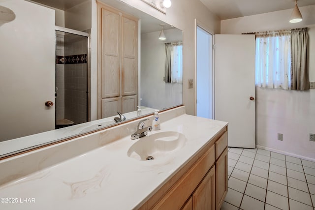 bathroom with a tile shower, vanity, baseboards, and tile patterned floors