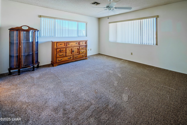 unfurnished bedroom featuring carpet floors, a ceiling fan, visible vents, and a textured ceiling