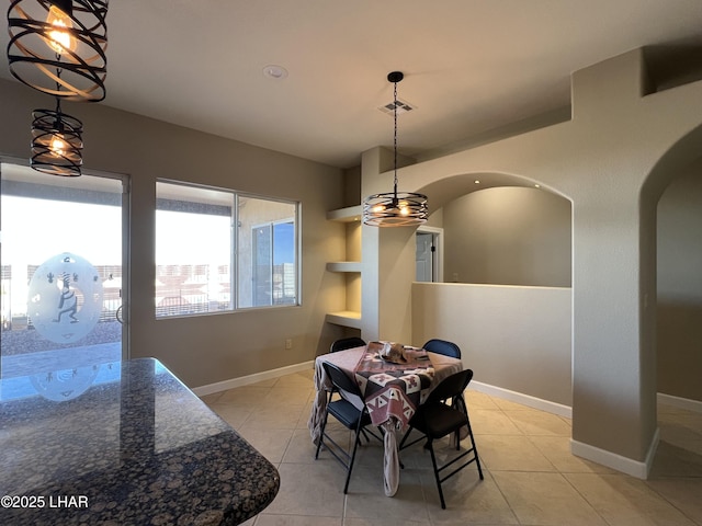 dining area with light tile patterned floors, arched walkways, visible vents, and baseboards