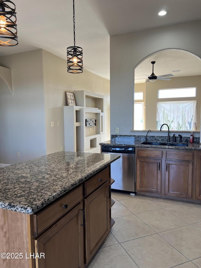 kitchen featuring arched walkways, dark stone counters, dishwasher, ceiling fan, and a sink