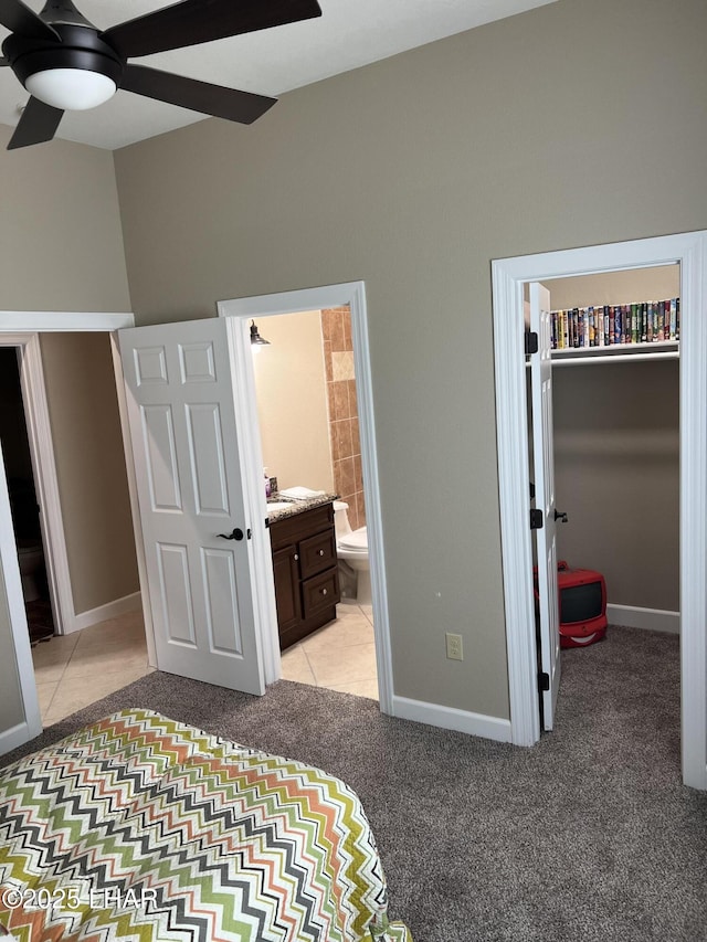 bedroom featuring a spacious closet, baseboards, connected bathroom, and light colored carpet