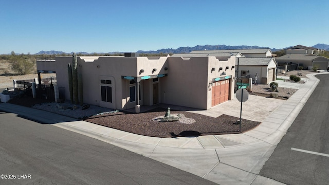 adobe home with driveway, a garage, a mountain view, and stucco siding