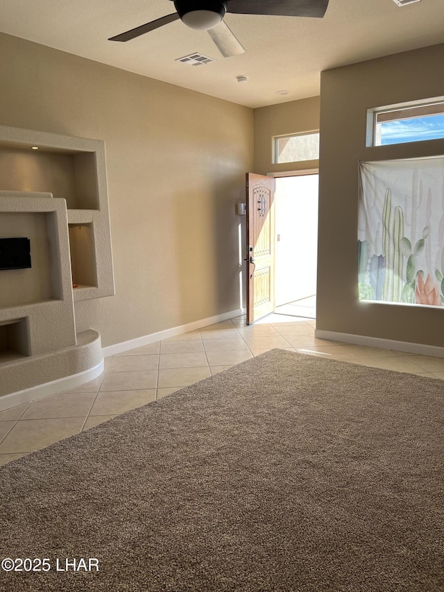 spare room with tile patterned flooring, visible vents, ceiling fan, and baseboards