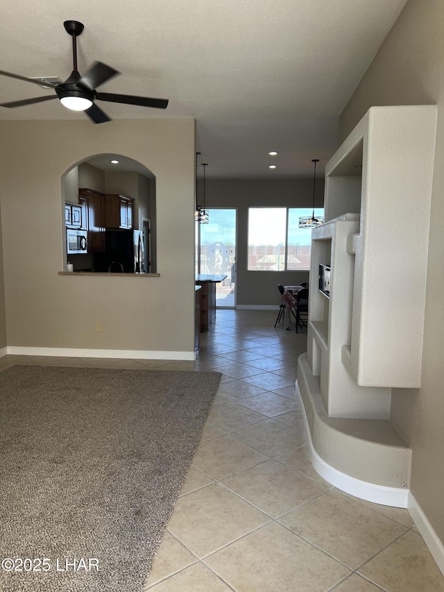 unfurnished living room with light tile patterned floors, baseboards, and a ceiling fan