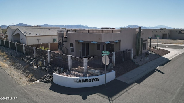 view of front of property with stairs, fence private yard, a mountain view, and stucco siding