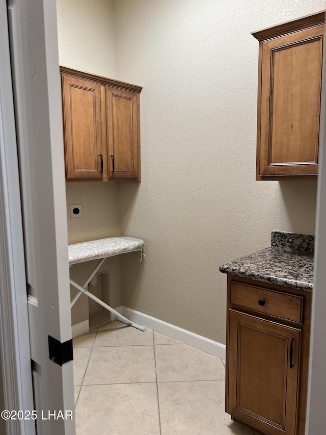 laundry room featuring light tile patterned floors, baseboards, cabinet space, and hookup for an electric dryer