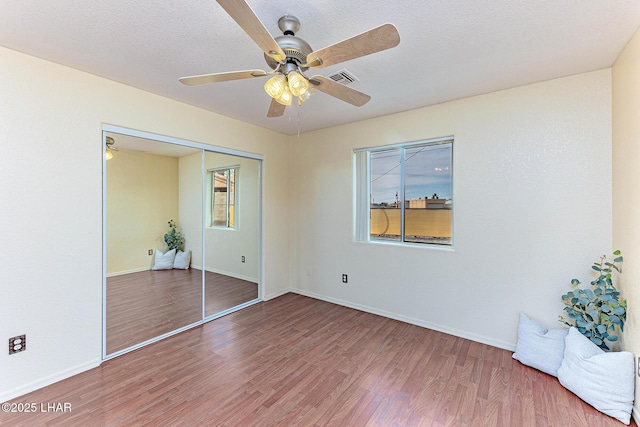 unfurnished bedroom with multiple windows, hardwood / wood-style floors, and a closet