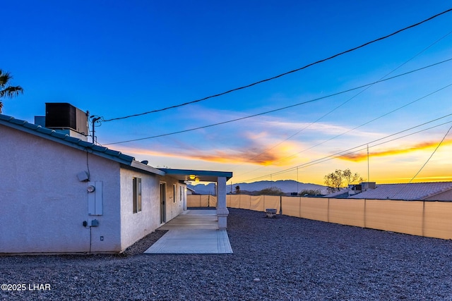 yard at dusk featuring cooling unit and a patio