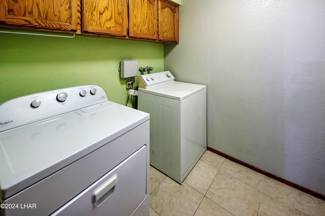 laundry area featuring light tile patterned flooring, cabinets, and washing machine and dryer