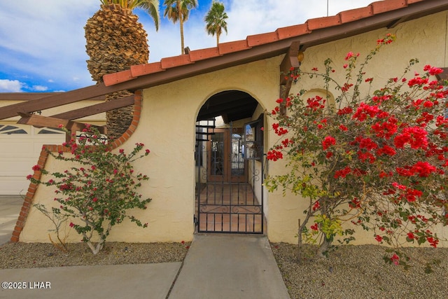 doorway to property featuring an attached garage and stucco siding