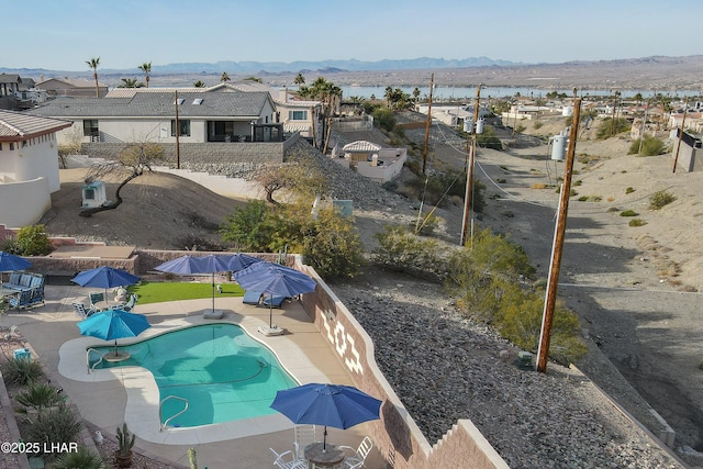 view of swimming pool with a fenced in pool, a fenced backyard, a residential view, a patio area, and a water and mountain view