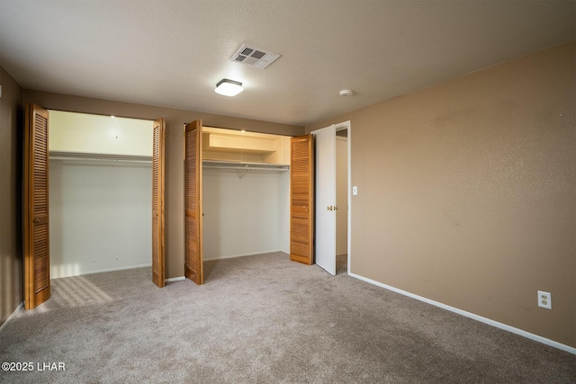 unfurnished bedroom with two closets and carpet floors