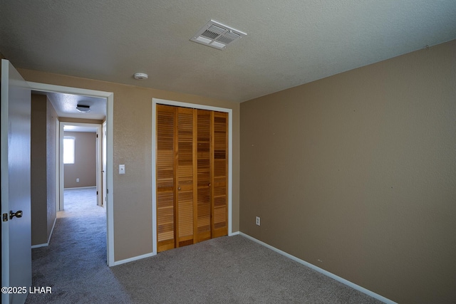 unfurnished bedroom featuring a closet, carpet flooring, and a textured ceiling