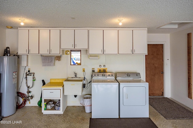 washroom featuring cabinet space, electric water heater, a textured ceiling, washing machine and dryer, and a sink