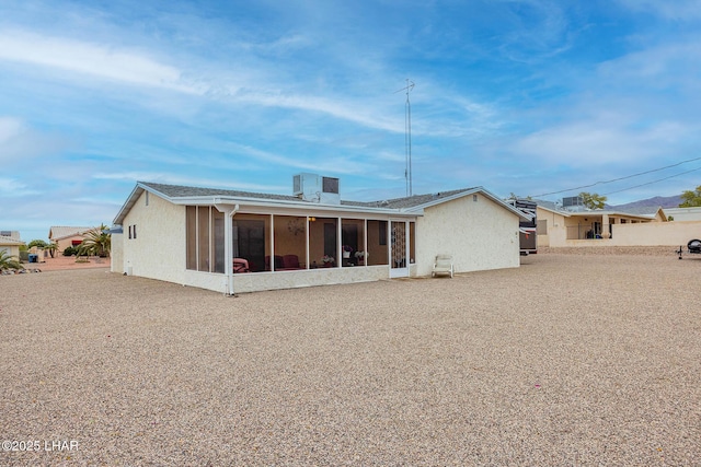 back of house featuring a sunroom and stucco siding