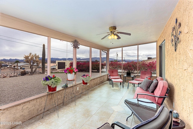 sunroom / solarium with a ceiling fan, a wealth of natural light, and a mountain view