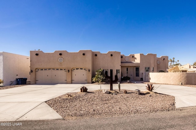 southwest-style home featuring driveway, fence, and stucco siding