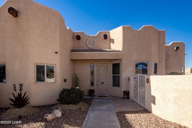 view of front facade featuring fence private yard, a gate, and stucco siding